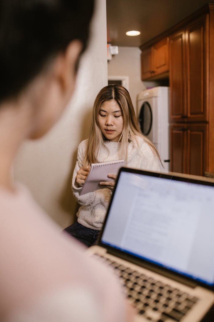 Young woman engaged in online learning at home with a laptop and notebook.